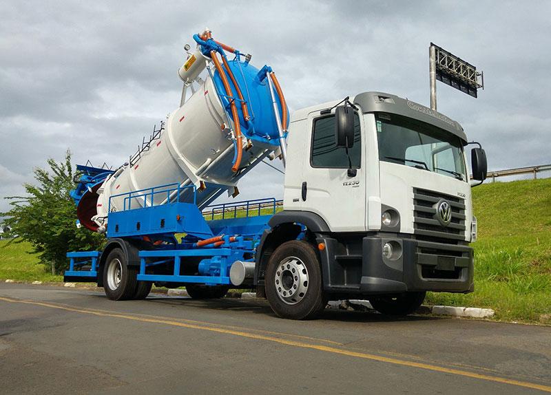 Caminhão combinado hidro vacuo estacionado, com o tanque levantado e a tampa aberta.