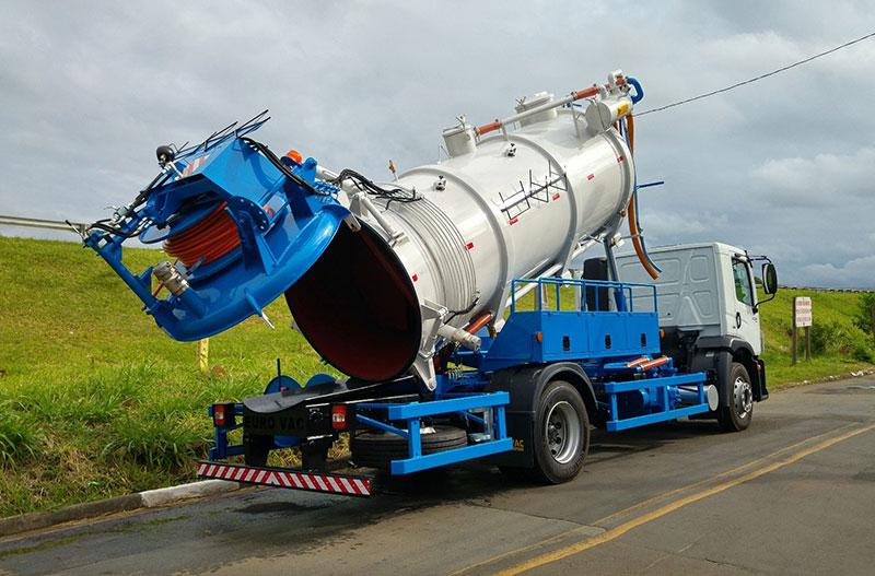 Caminhão combinado hidro vacuo estacionado, com o tanque levantado e a tampa aberta.
